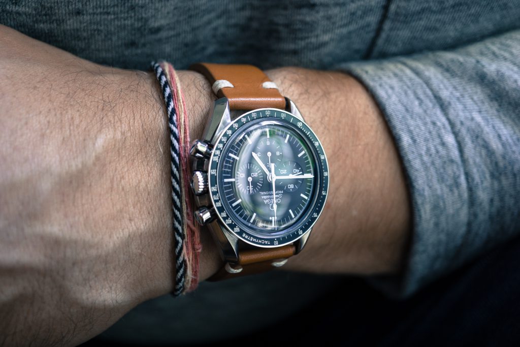 Gros plan sur le poignet d'un homme avec une montre Oméga et des bracelets
